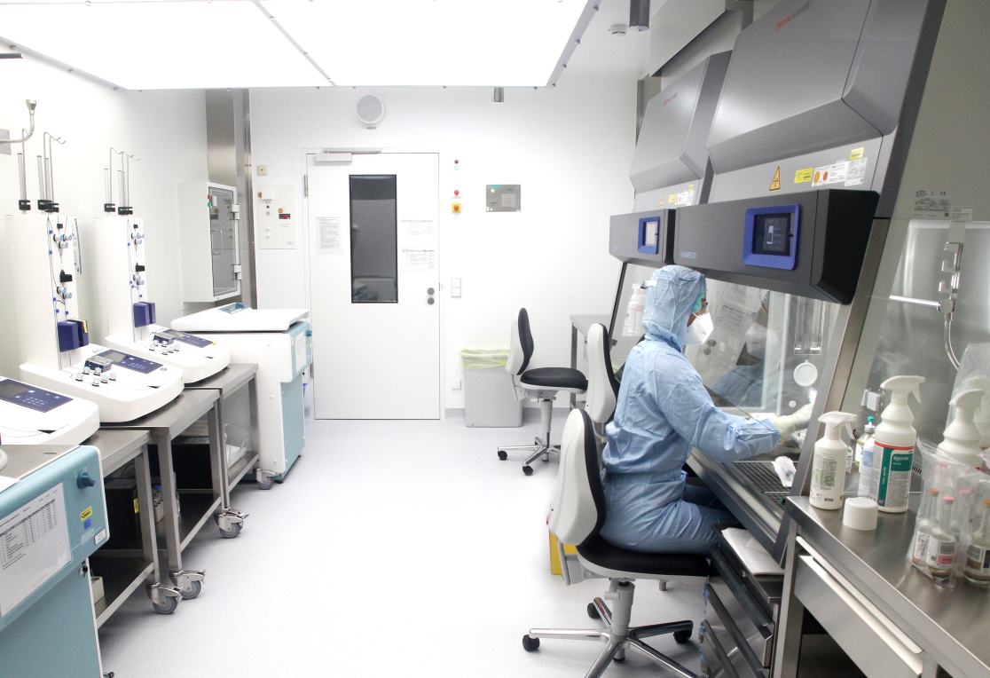 Ein Mitarbeiter in steriler Schutzausrüstung sitzt in einem Reinraum zur Arzneimittelherstellung.