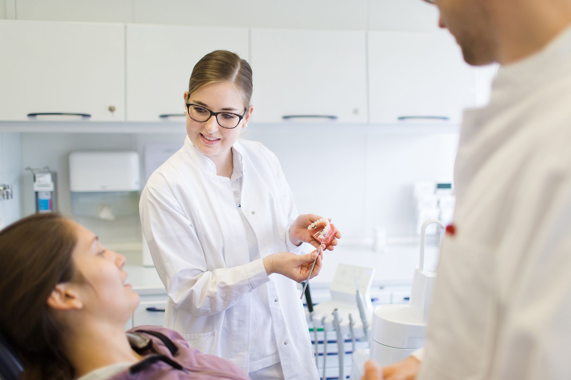 Prophylaxehelferin erjkärt am Zahnmodell die Entstehung von Zahnstein