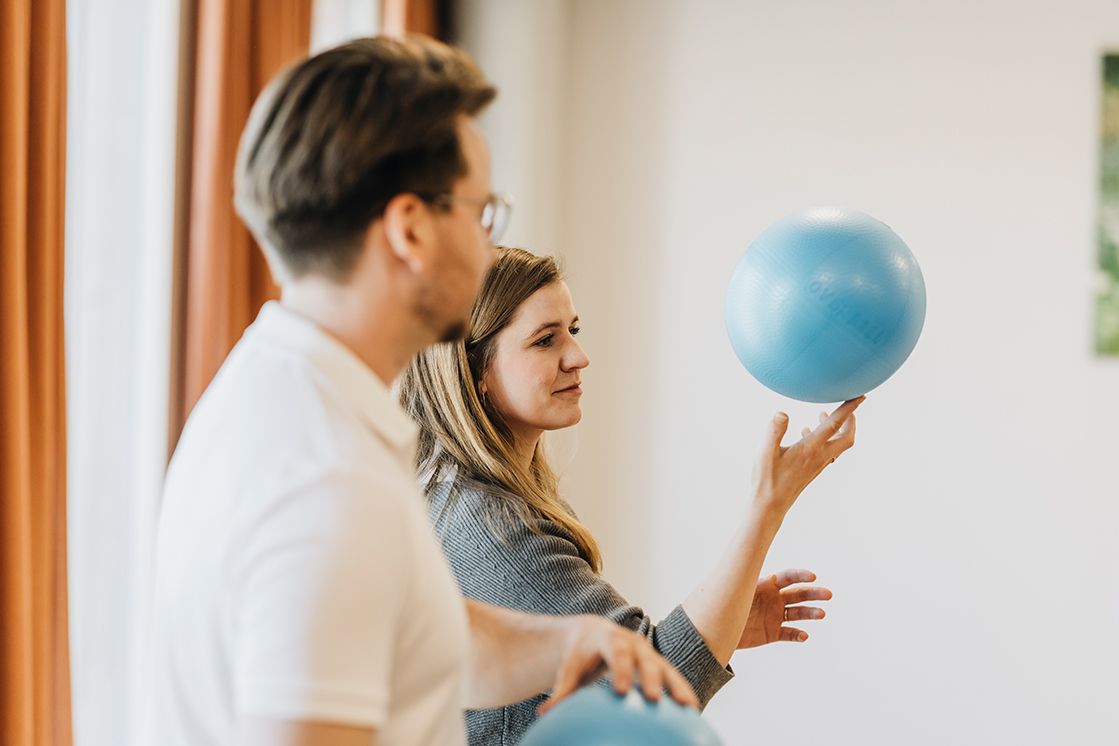 zwei Personen halten jeweils einen Ball in der Hand, eine Raum balanciert ihren Ball auf einem Finger, der nebenstehende Mann hält seinen Ball mit beiden Händen fest.