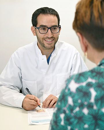 Stefano Fusco steht im Arztkittel im Stationsflur