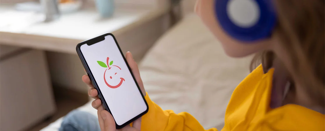 Mädchen mit Kopfhörern hält Smartphone mit App in der Hand