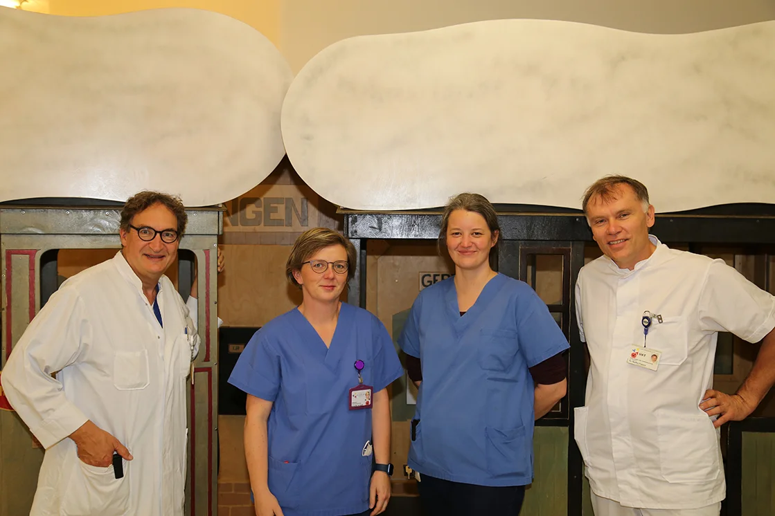 Gruppenfoto des Sprechstundenteams vor dem Kinderzug im Spielbereich der Klinik