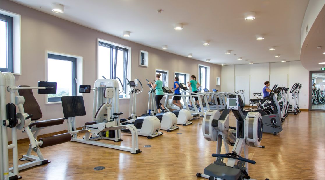 Personen trainieren an Geräten im Sportraum