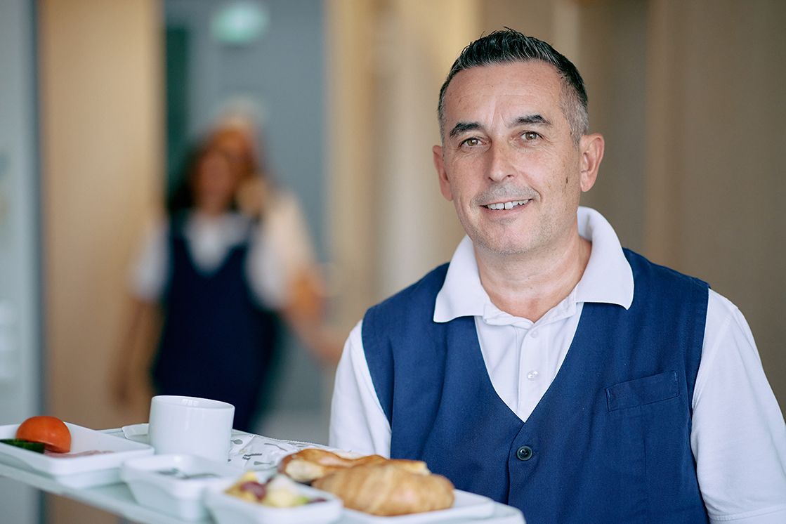 Servicekraft bringt Tablett mit Essen
