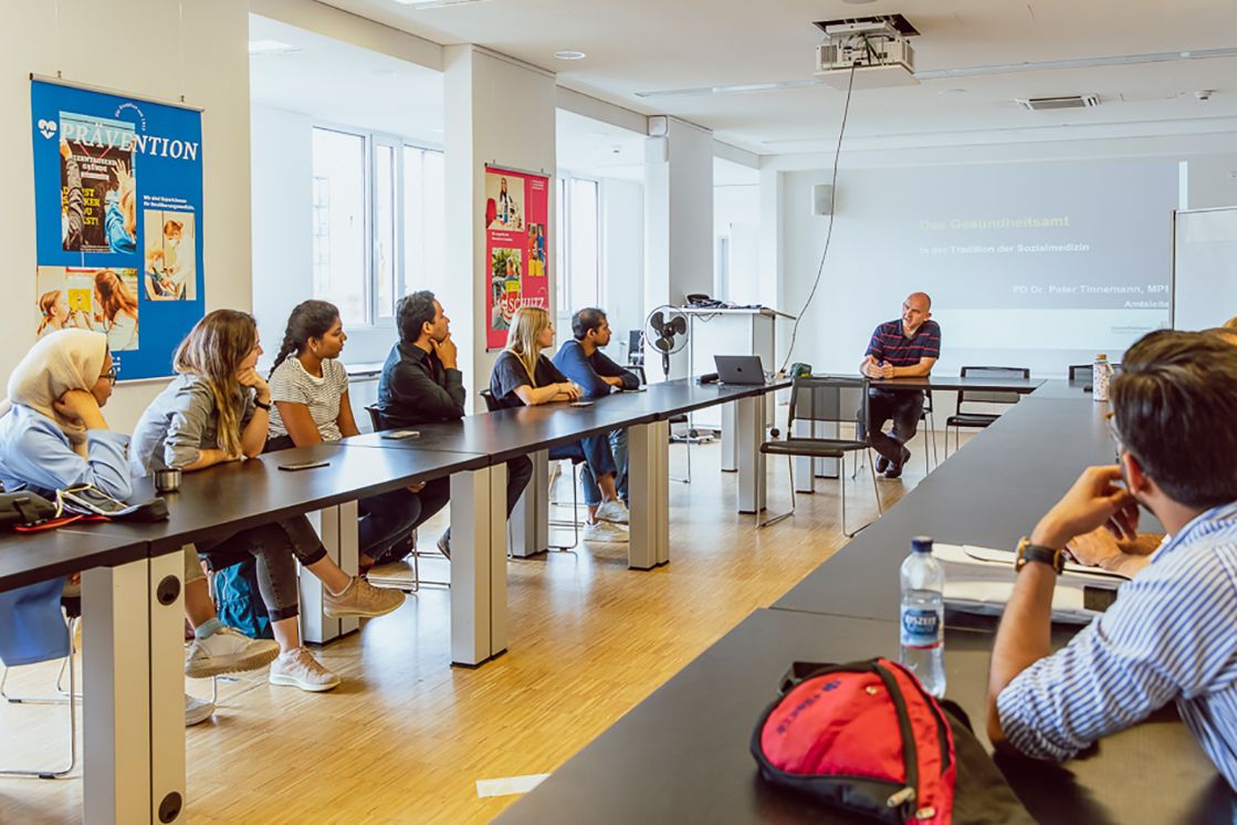 Dozent hält einen Vortrag und Studierende hören zu