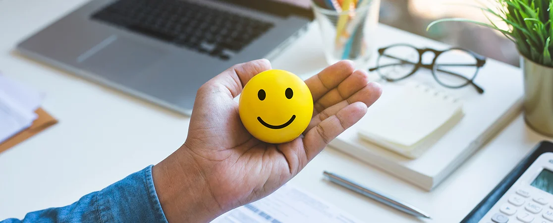 Hand mit Smiley vor einem Büroarbeitsplatz