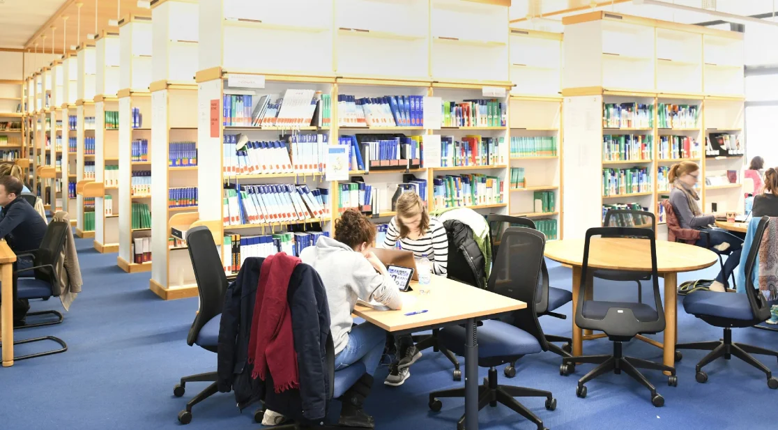 Zwei Personen sitze an eine Tisch in der Bibliothek