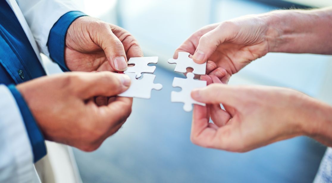 Zwei Menschen halten pasende Puzzleteile aneinander