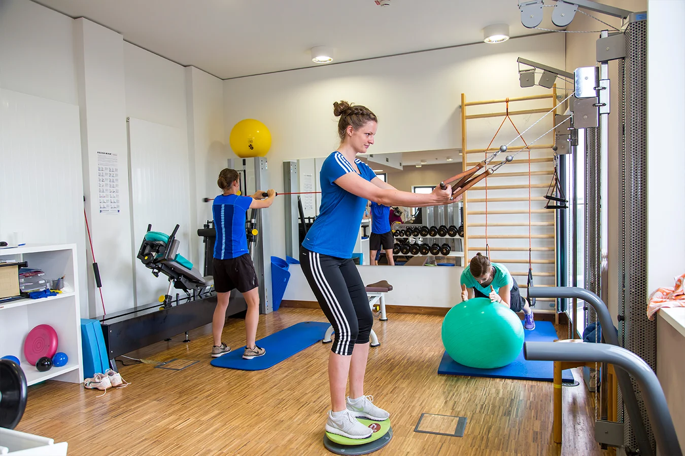 Personen trainieren mit verschiedenen Trainingsgeräten und Bällen