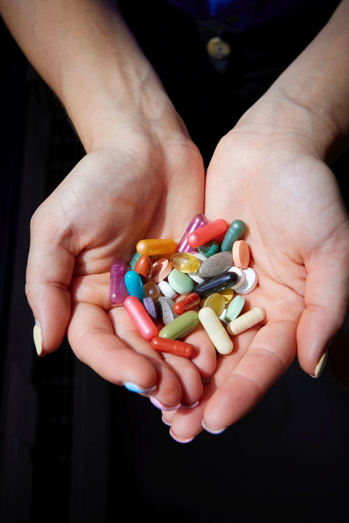 Two hands filled with colorful pills