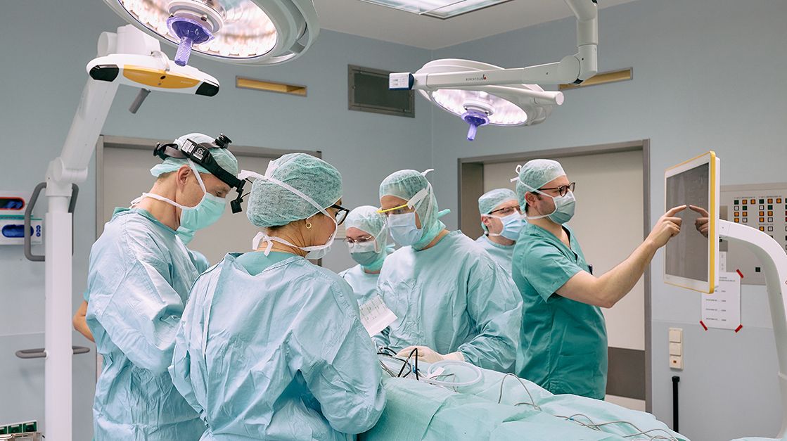 Grün gekleidete Personen im OP Saal operieren