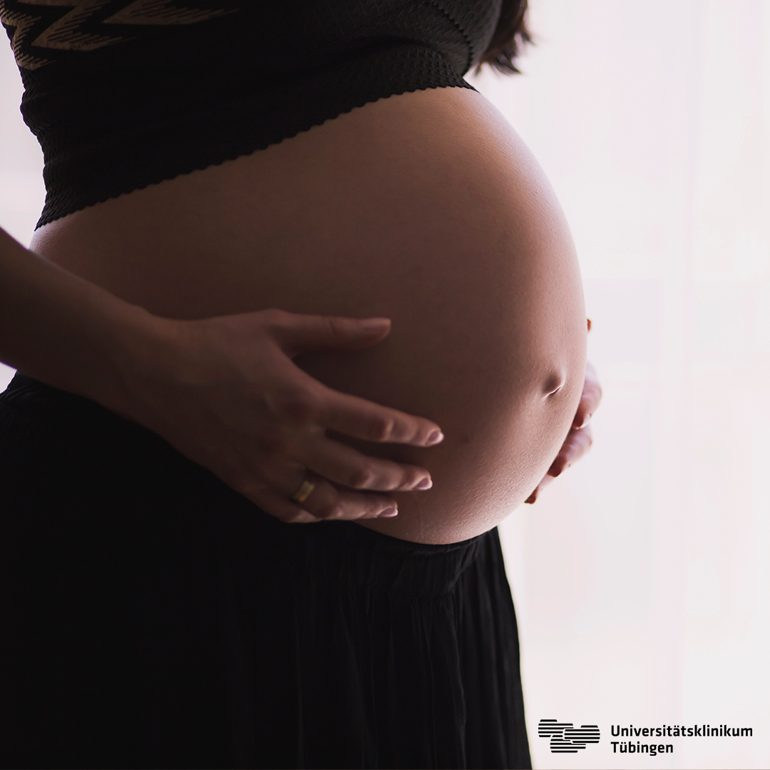 Eine schwangere Frau hält ihre Hände an ihren Bauch.