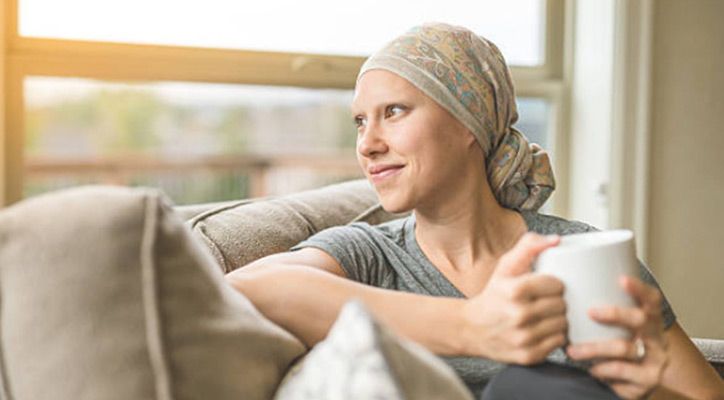 Frau mit Kopftuch und Tasse sitzt auf einem Sofa