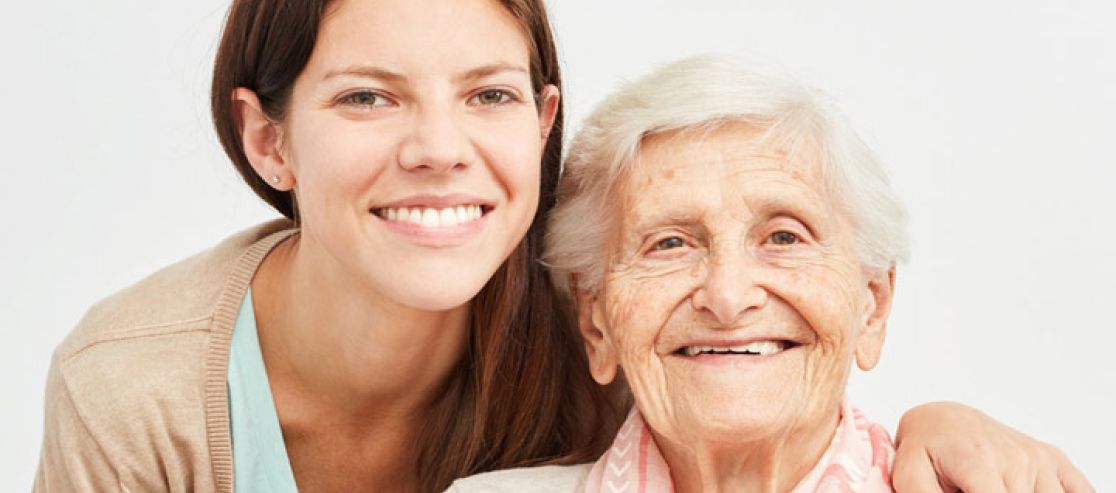 Junge Frau kümmert sich um alte Frau im Rollstuhl