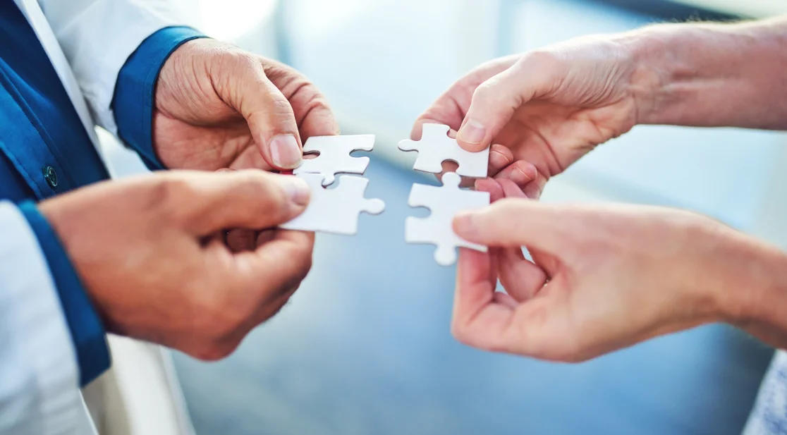 Zwei Menschen halten pasende Puzzleteile aneinander