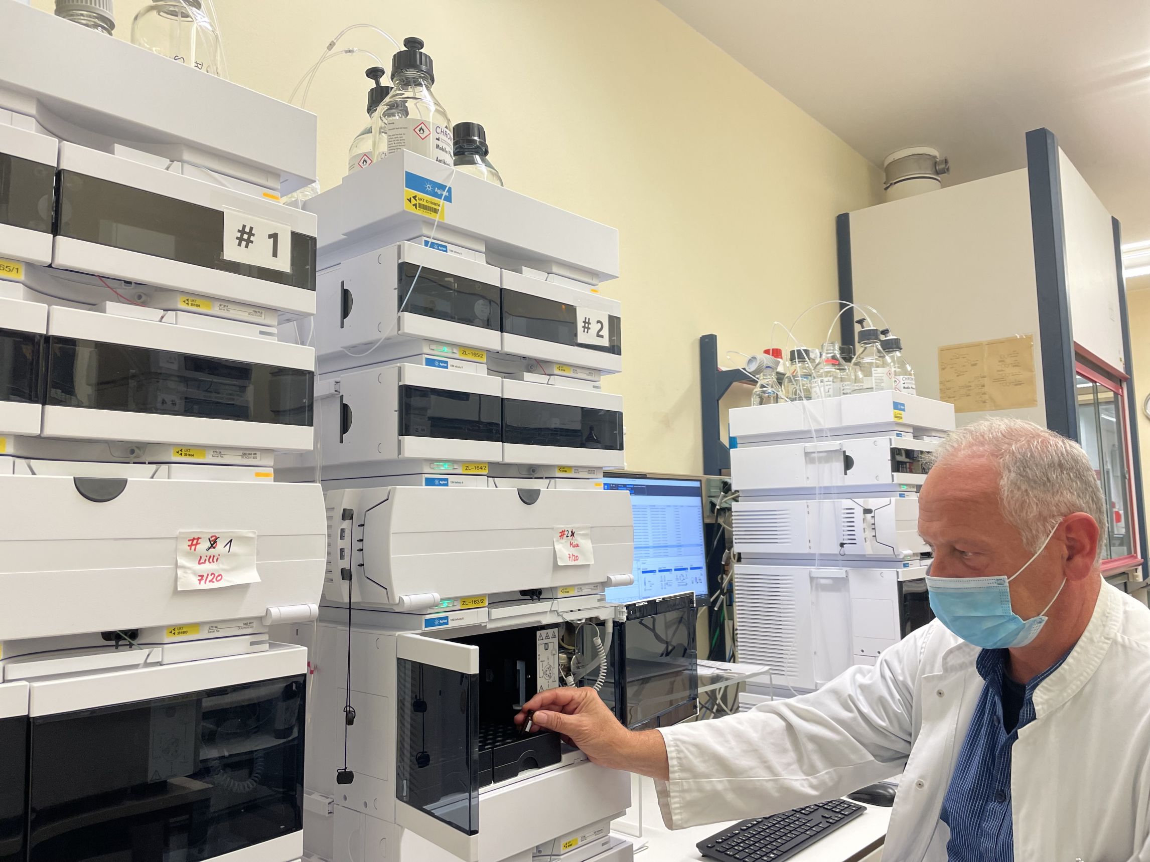 Ein Gerät im Labor zur Untersuchung von Antibiotikaspiegeln. Ein Mitarbeiter mit Maske bedient das Gerät.