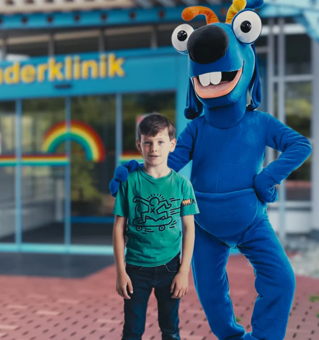 Moritz mit Maskottchen Jojo vor der Kinderklinik