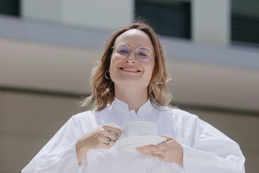 Die Anästhesistin im Arztkittel trinkt einen Kaffee in der Sonne