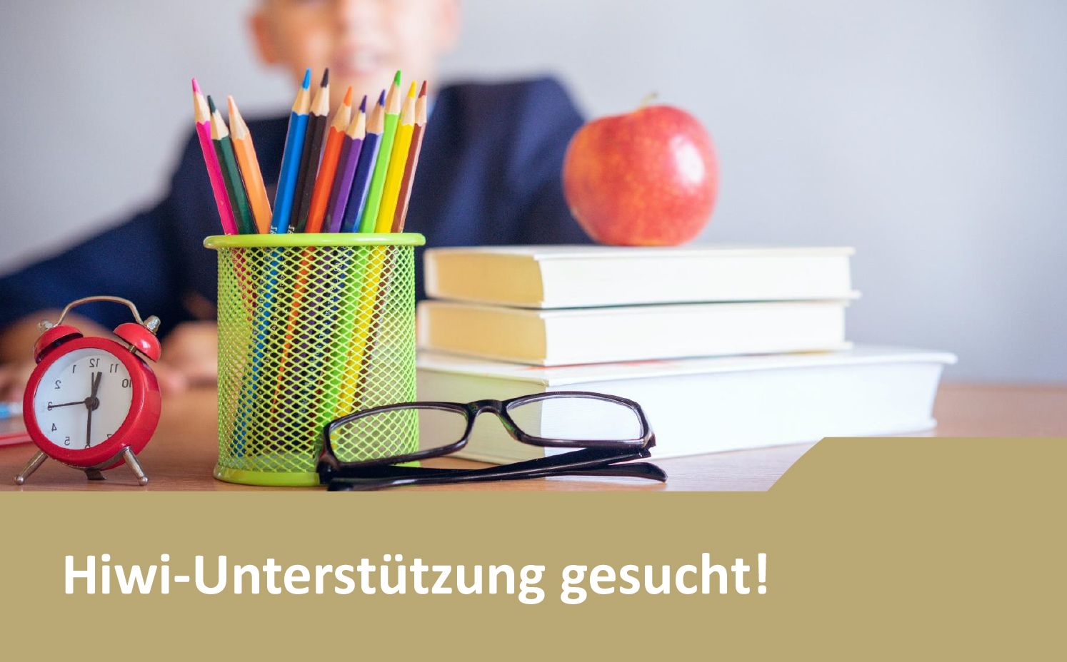 Hiwi Unterstützung gesucht! Schreibtisch mit bunten Stiften, Büchern und Apfel