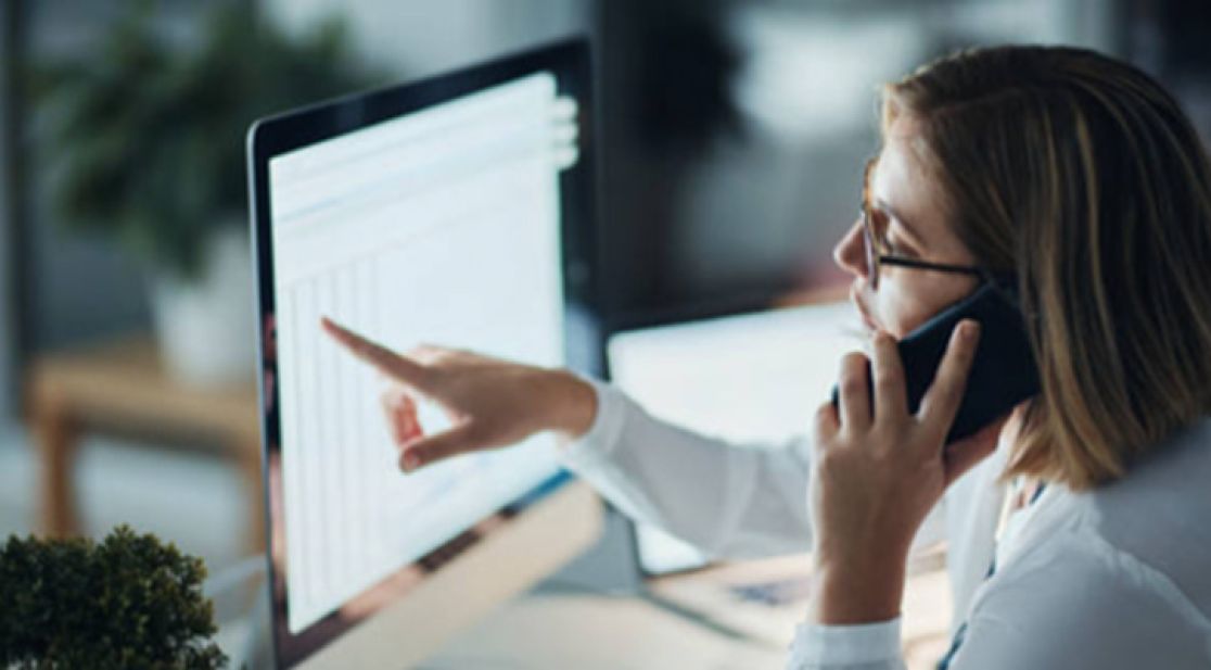Schmuckbild: Frau telefoniert vor Bildschirm und liest dort mit dem Finger Termine ab