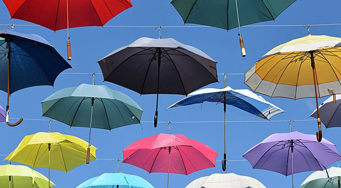 Schmuckbild bunte Schirme vor blauem Himmel