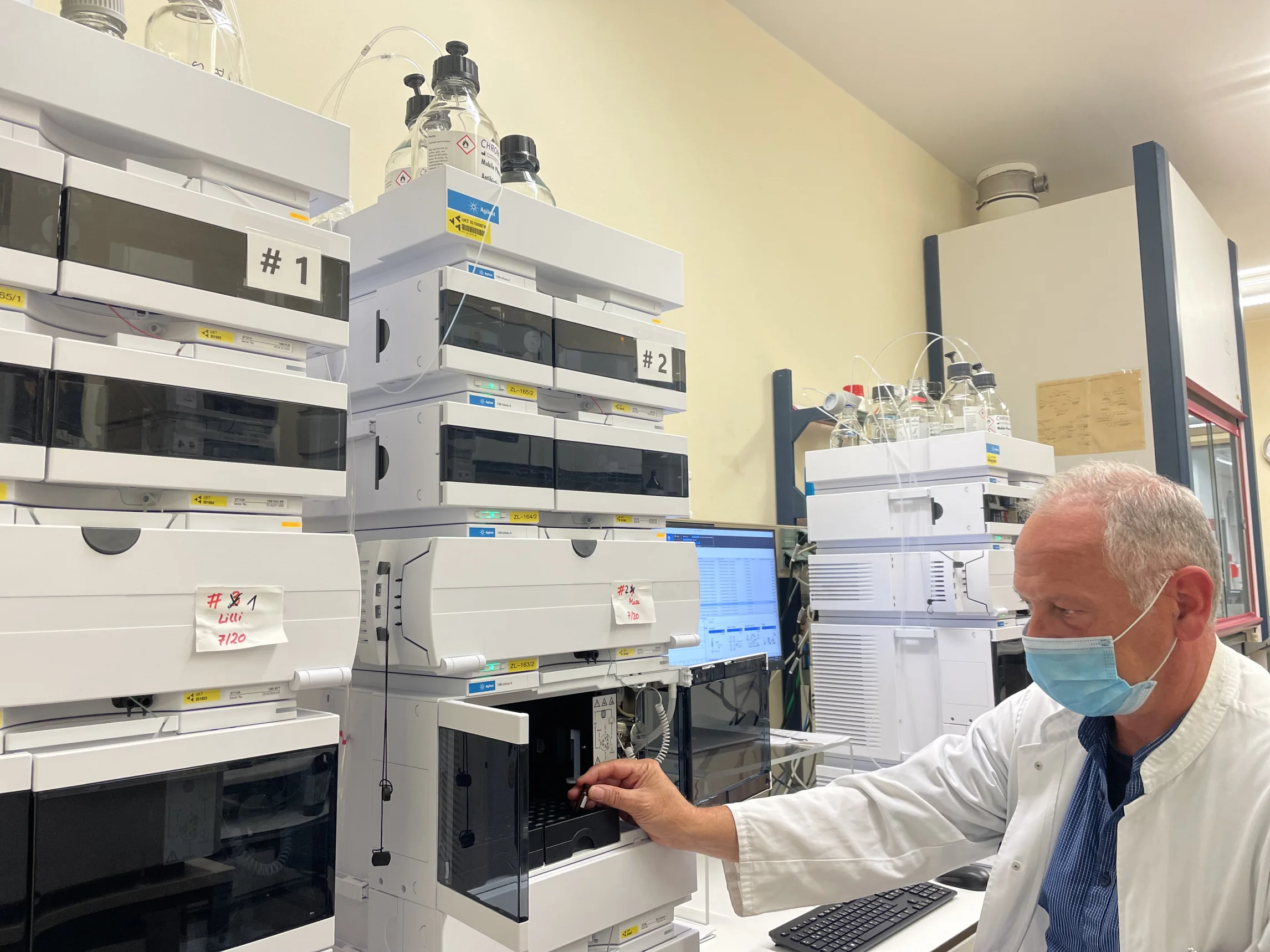 Ein Gerät im Labor zur Untersuchung von Antibiotikaspiegeln. Ein Mitarbeiter mit Maske bedient das Gerät.