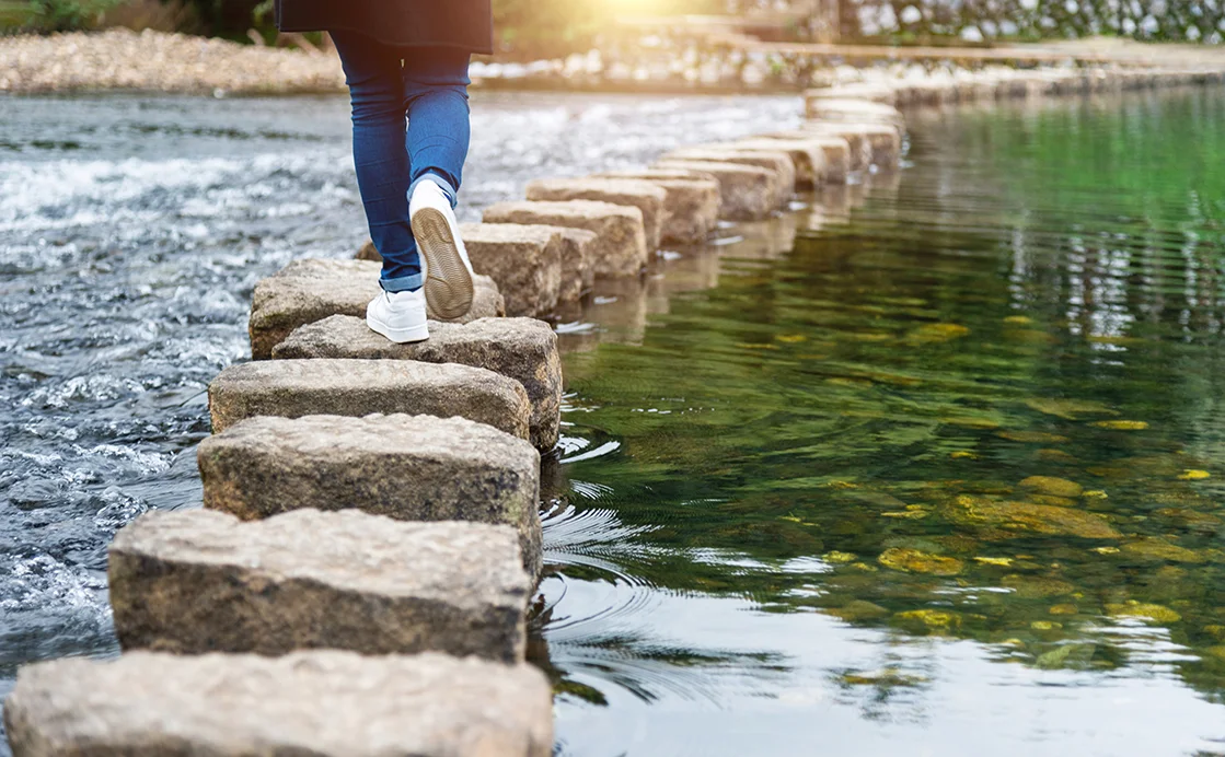 Mensch geht über Steine im Wasser