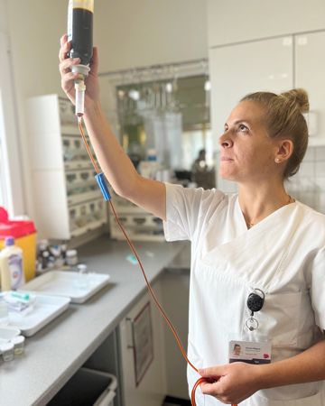 Verena Wagner am Fenster hält eine Blutkonserve gegen das Licht