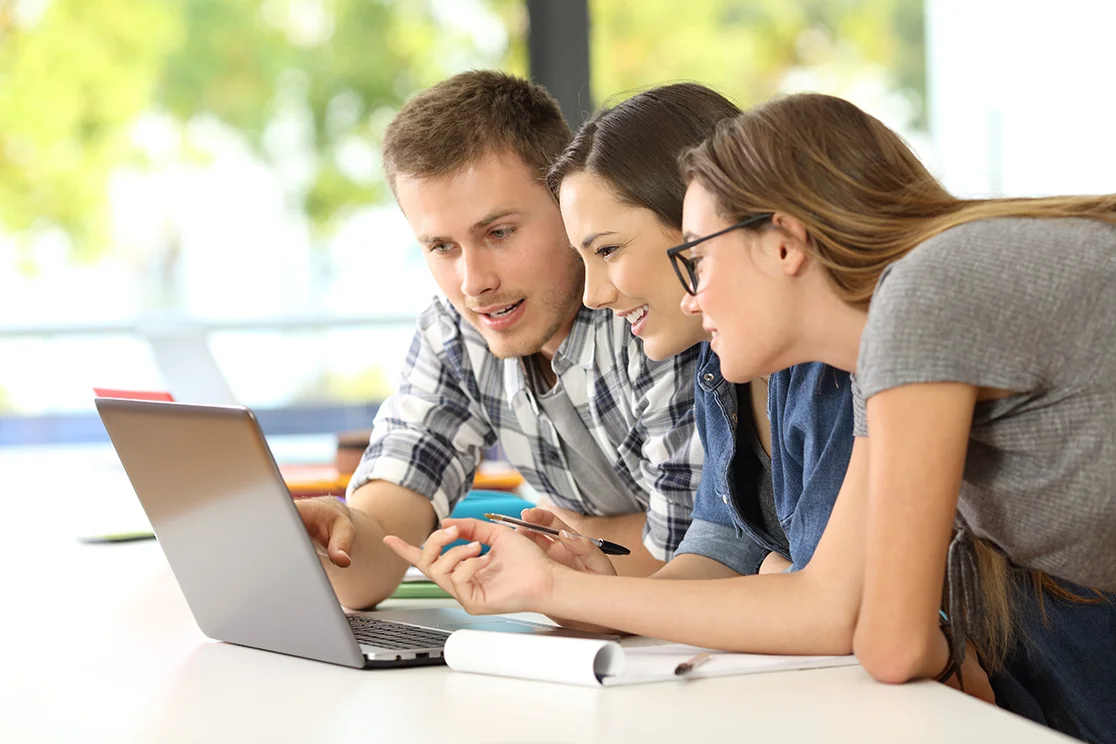 Drei Menschen schauen auf Laptop