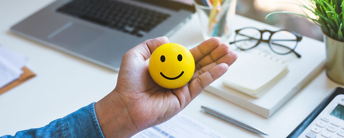 Hand mit Smiley vor einem Büroarbeitsplatz