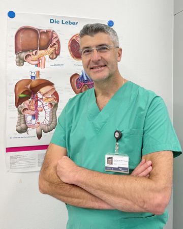 Prof. Nadalin im OP-Kittel vor einem Leber-Schaubild
