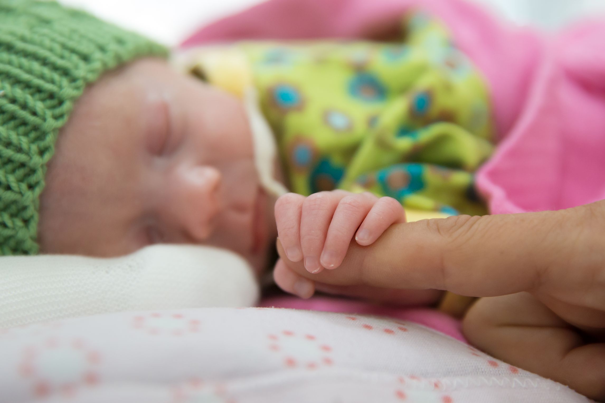 Baby hält den Finger seiner Mama.