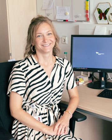 Aline Schechtel sitzt am Schreibtisch und lächelt