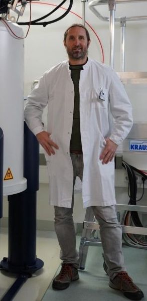 Christoph Trautwein steht vor einem Laborgerät