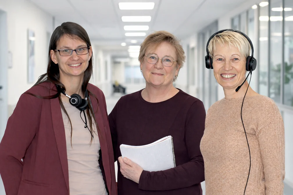 Die drei Krebswegweiserinnen blicken in die Kamera vor Krankenhaushintergrund (Hintergrund mit KI erstellt)
