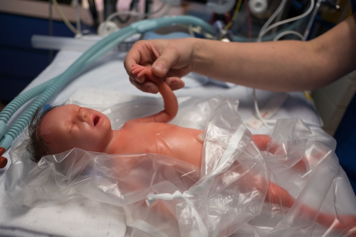 Eine Person hält die Hand der Simulationspuppe.