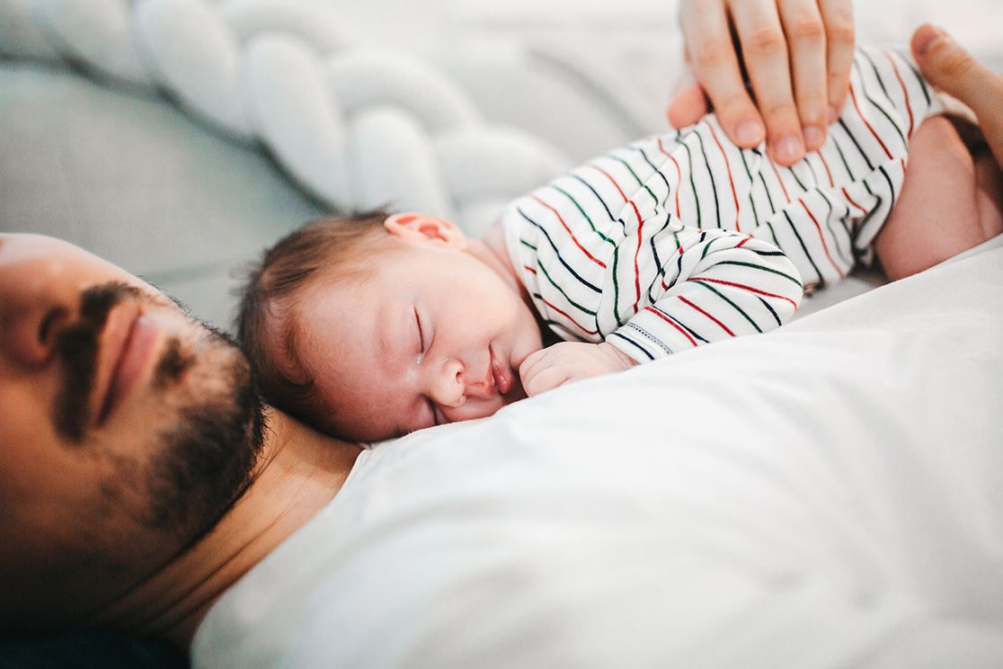 Vater liegt mit Kind auf der Brust