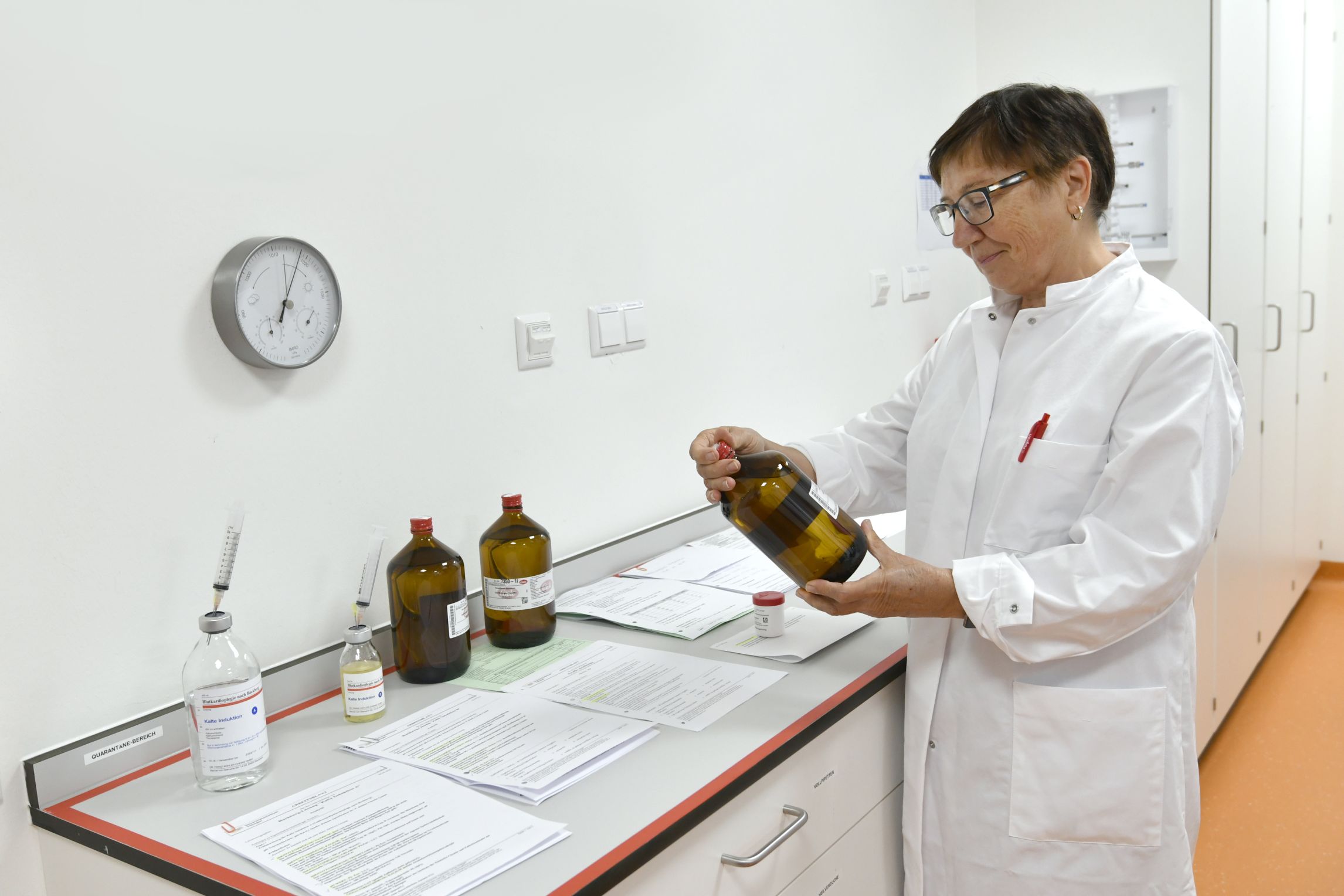 Mitarbeiterin prüft Arzneimittelbehältnis.