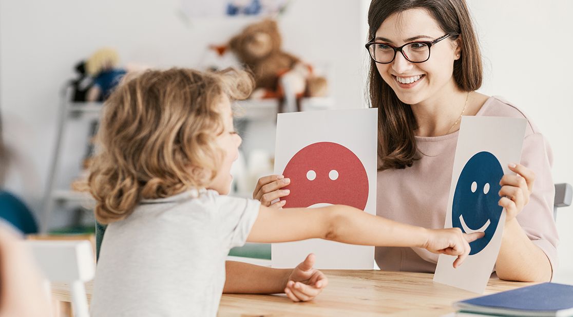Emotion-Emoticons gezeigt von einer Psychologin während einer Therapiesitzung mit einem Kind