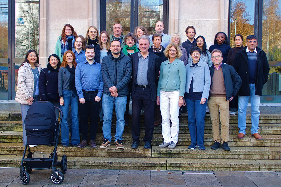 Gruppenfoto: Team auf der Treppe vor dem Institut