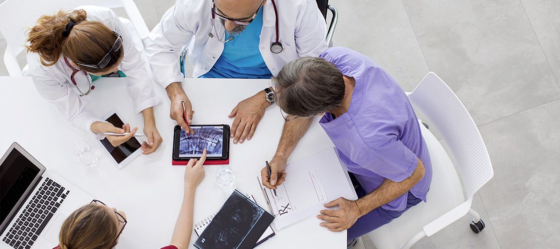 Schmuckbild: Ärzte sitzen an einem runden Tisch und besprechen sich