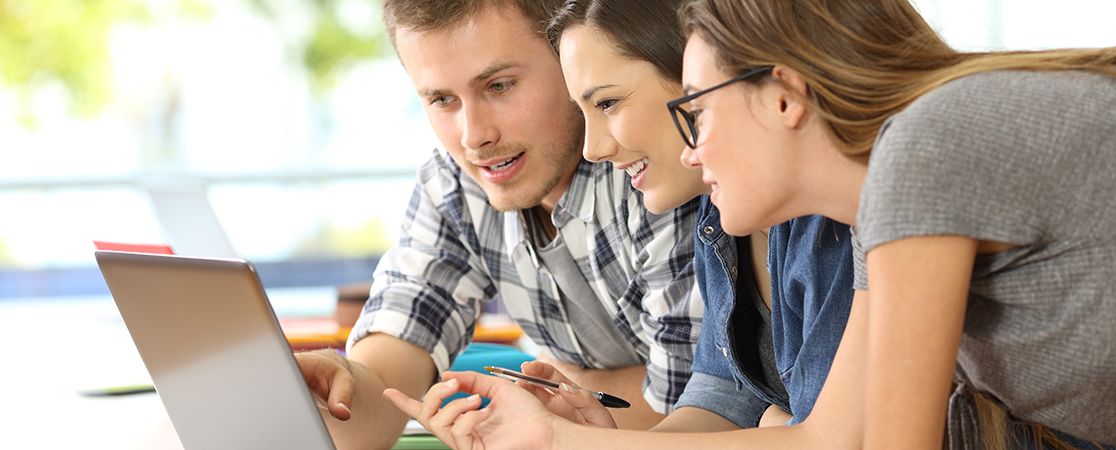 Drei Menschen schauen auf Laptop