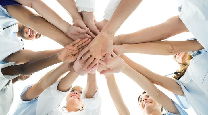 Menschen stehen in Kreis und legen die Hände aufeinander