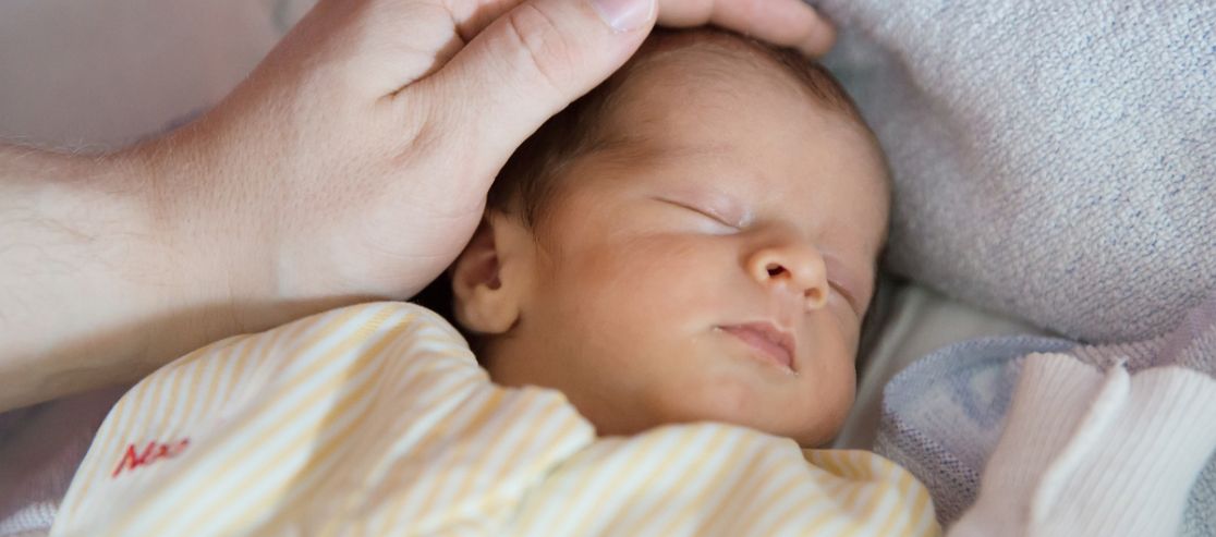 Neugeborenes wird über den Kopf gestreichelt
