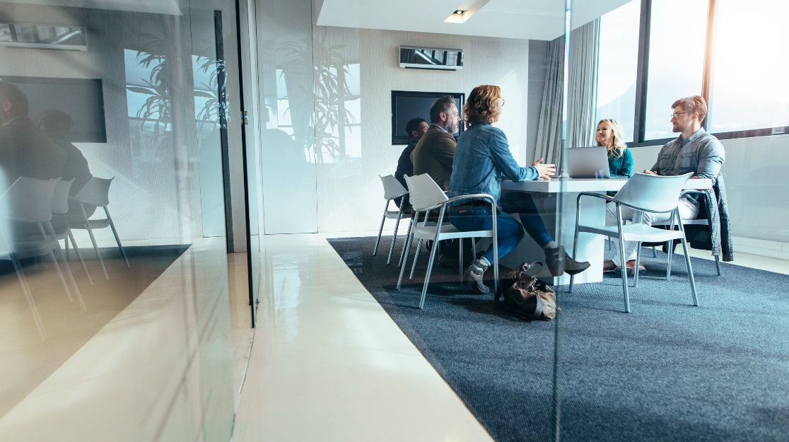 Fünf Menschen an einem Tisch in einem Besprechungsraum