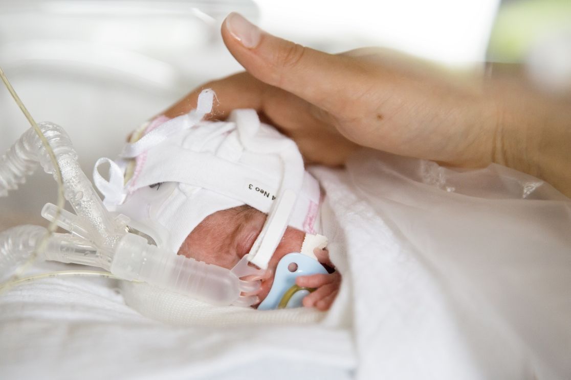 Neugeborenes mit streichelnder Hand