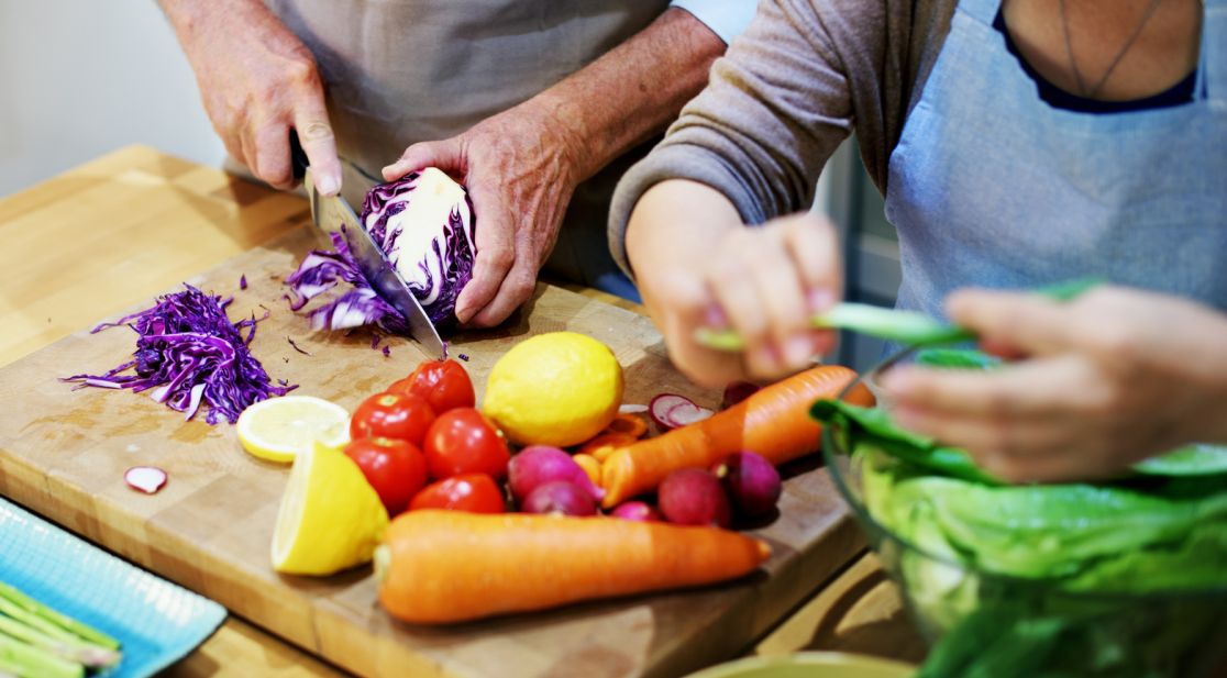 Schmuckbil: Zwei Personen schneiden Gemüse auf einem Küchenbrett
