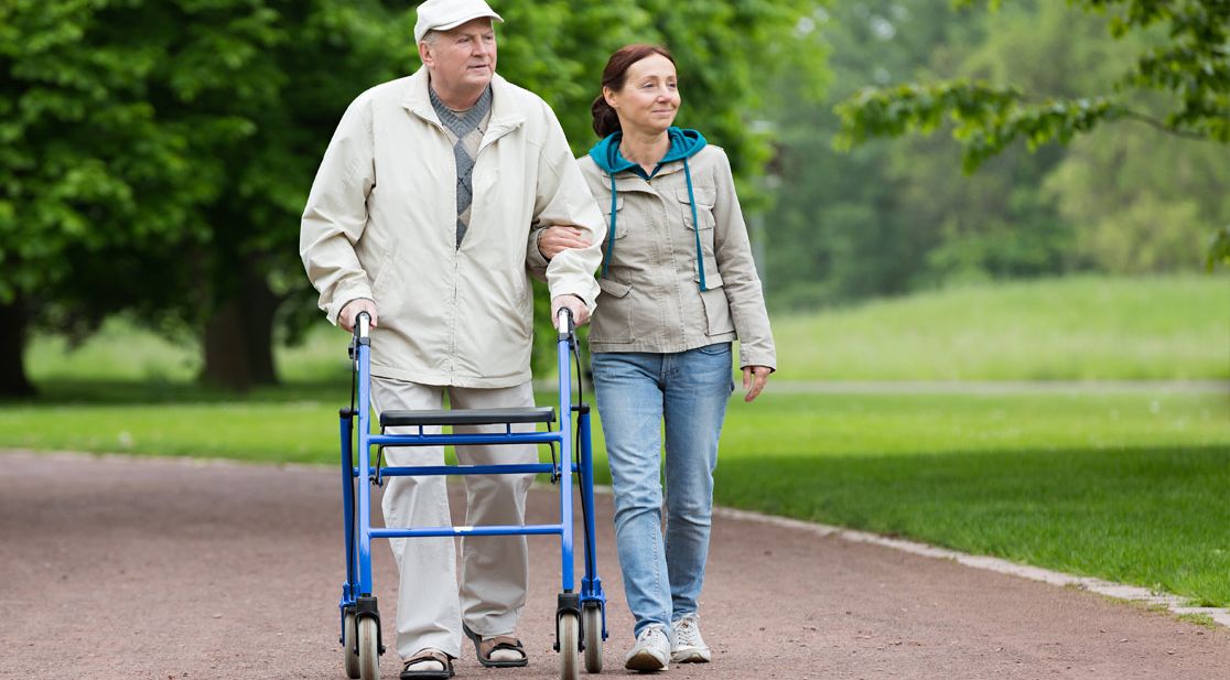 Mann mit Rollator, Frau begleitet ihn