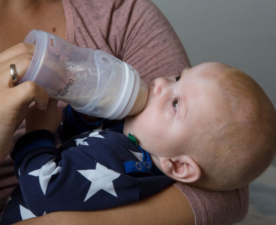 Baby drinks from a milk bottle