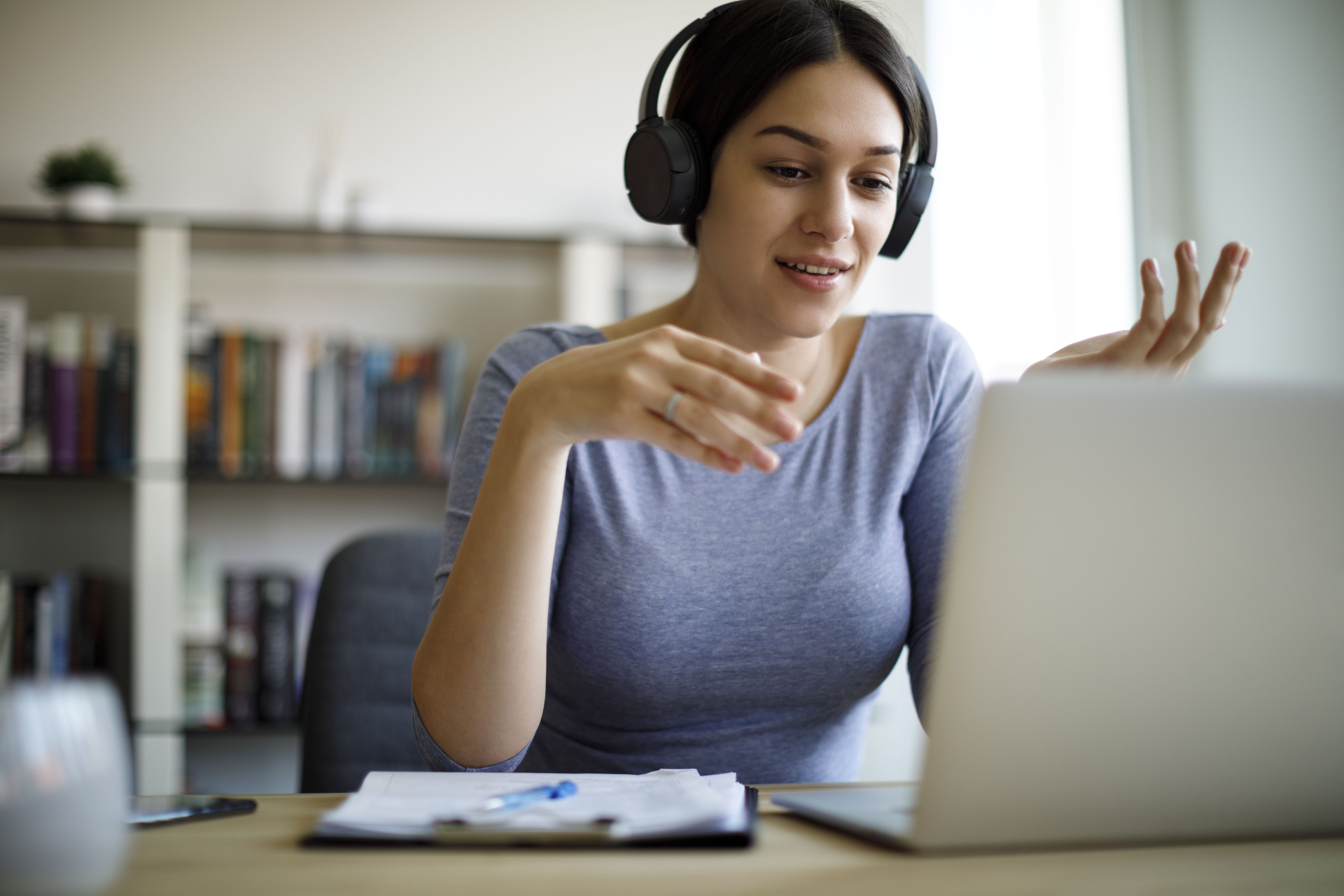 Frau am Laptop mit Kopfhörern im Online-Gespräch
